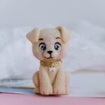 A charming handmade puppy figurine displayed on a soft pastel background, ideal for decoration.